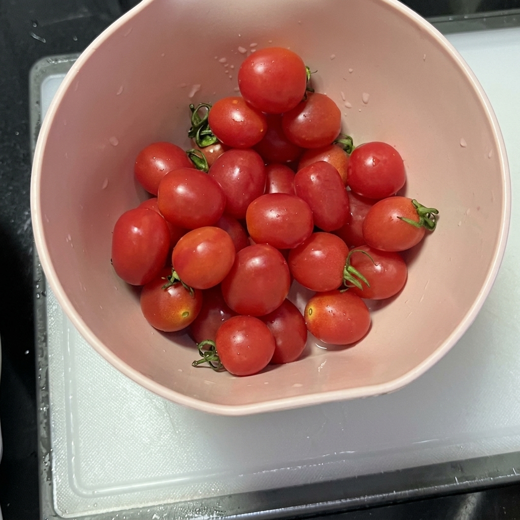 Tomates cherry cortados por la mitad sobre una tabla de cortar limpia.