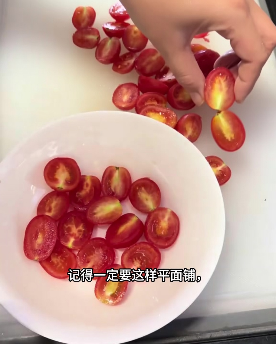 Primer plano de tomates cherry cortados dispuestos en una sola capa en un tazón blanco.