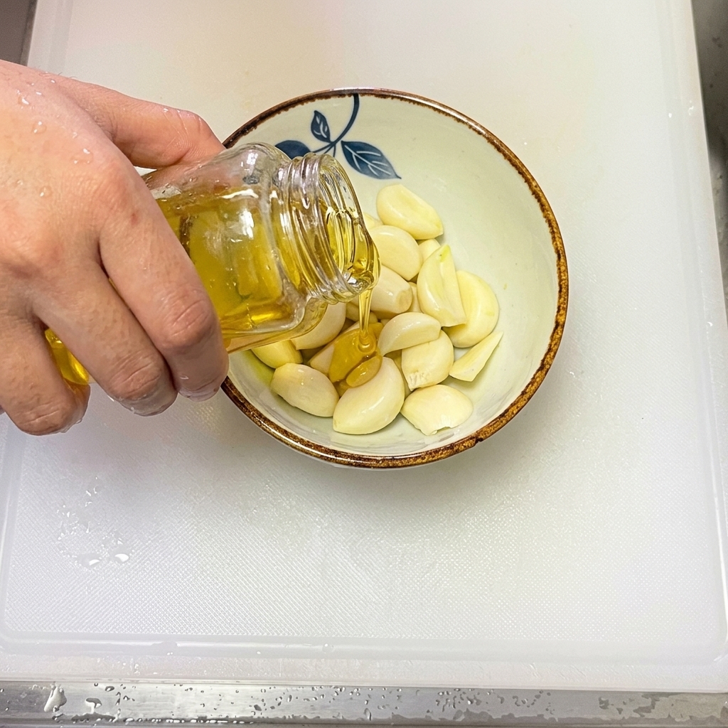 Aceite de oliva siendo vertido en un tazón que contiene ajo fresco laminado.