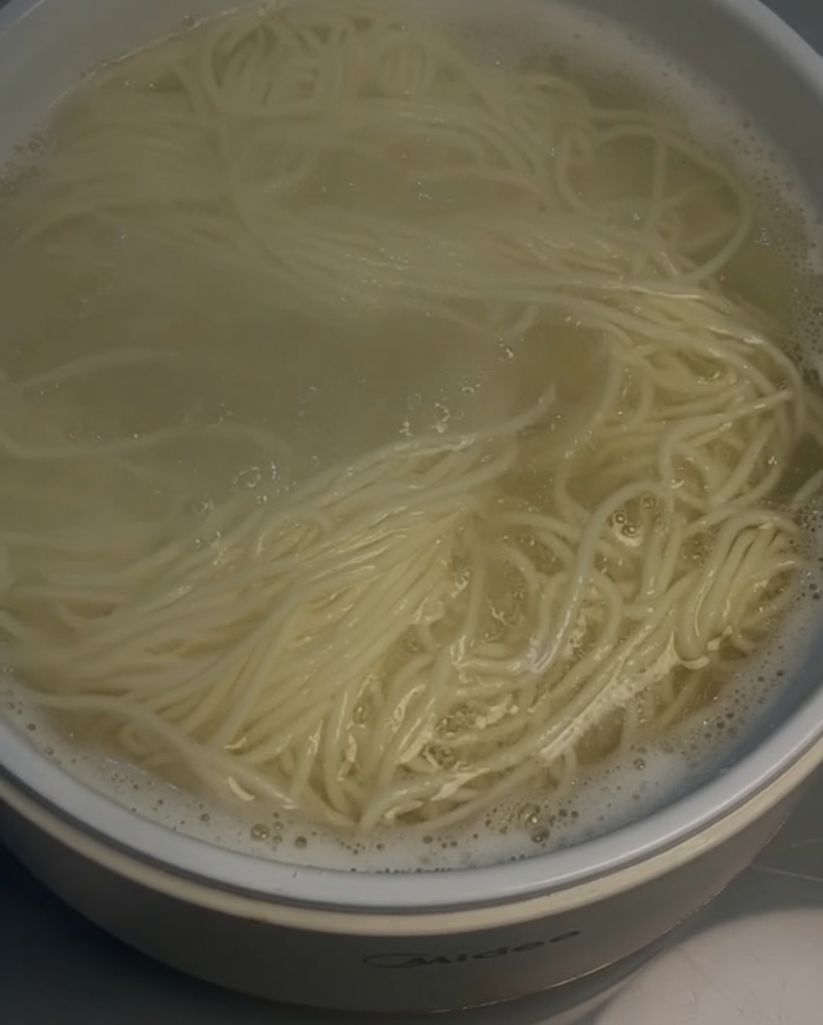 Un colador escurriendo los fideos cocidos de una olla.