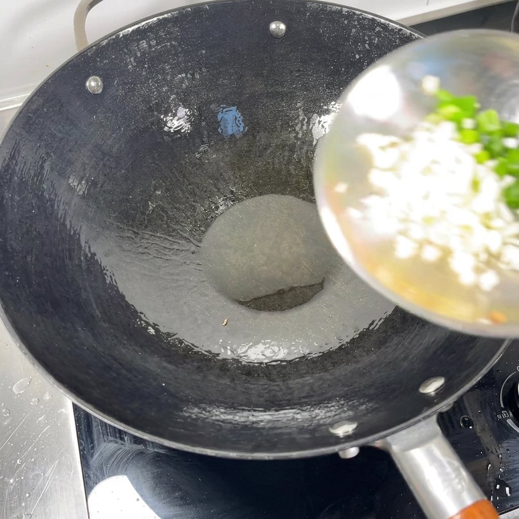 Cebolleta y ajo picados añadiéndose a un wok caliente con aceite.