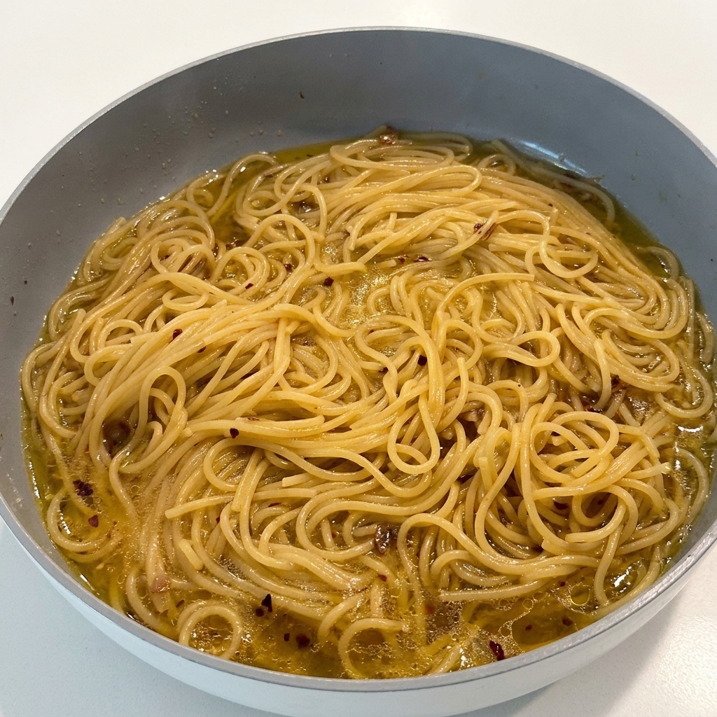 Sazonando la pasta con pimienta negra mientras está en la sartén.