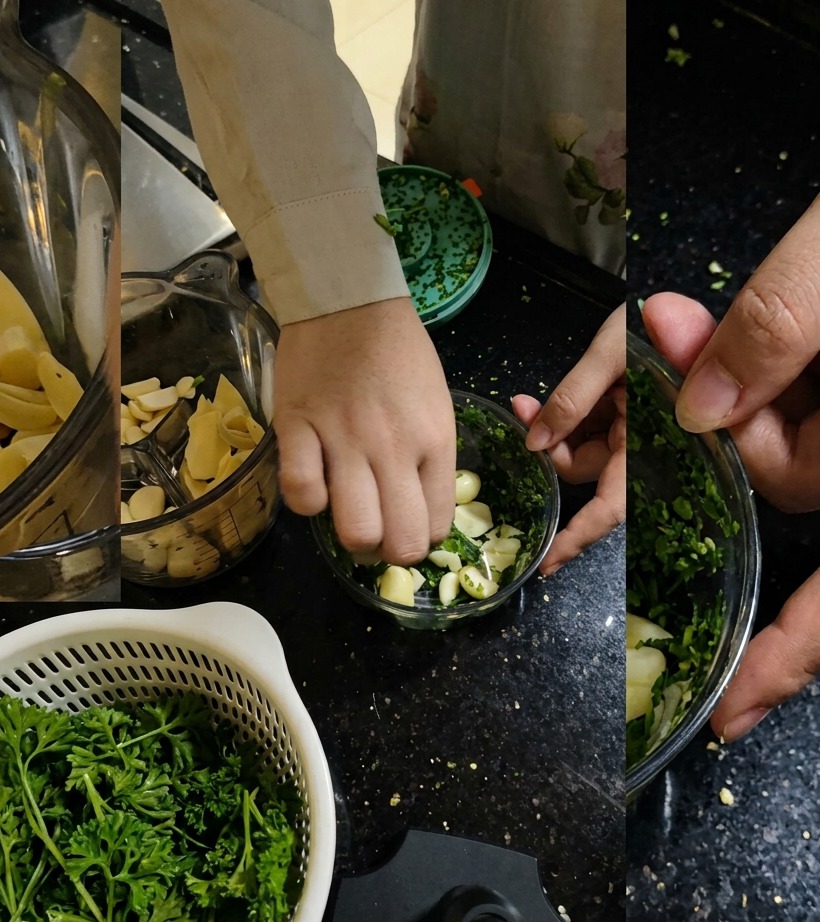 Perejil fresco siendo añadido al procesador de alimentos junto con los dientes de ajo.