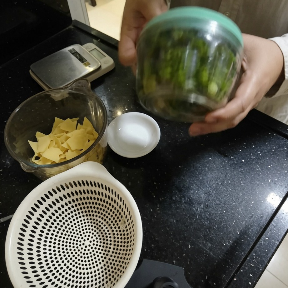 Una mano operando un procesador de alimentos de cuerda para picar las hierbas.