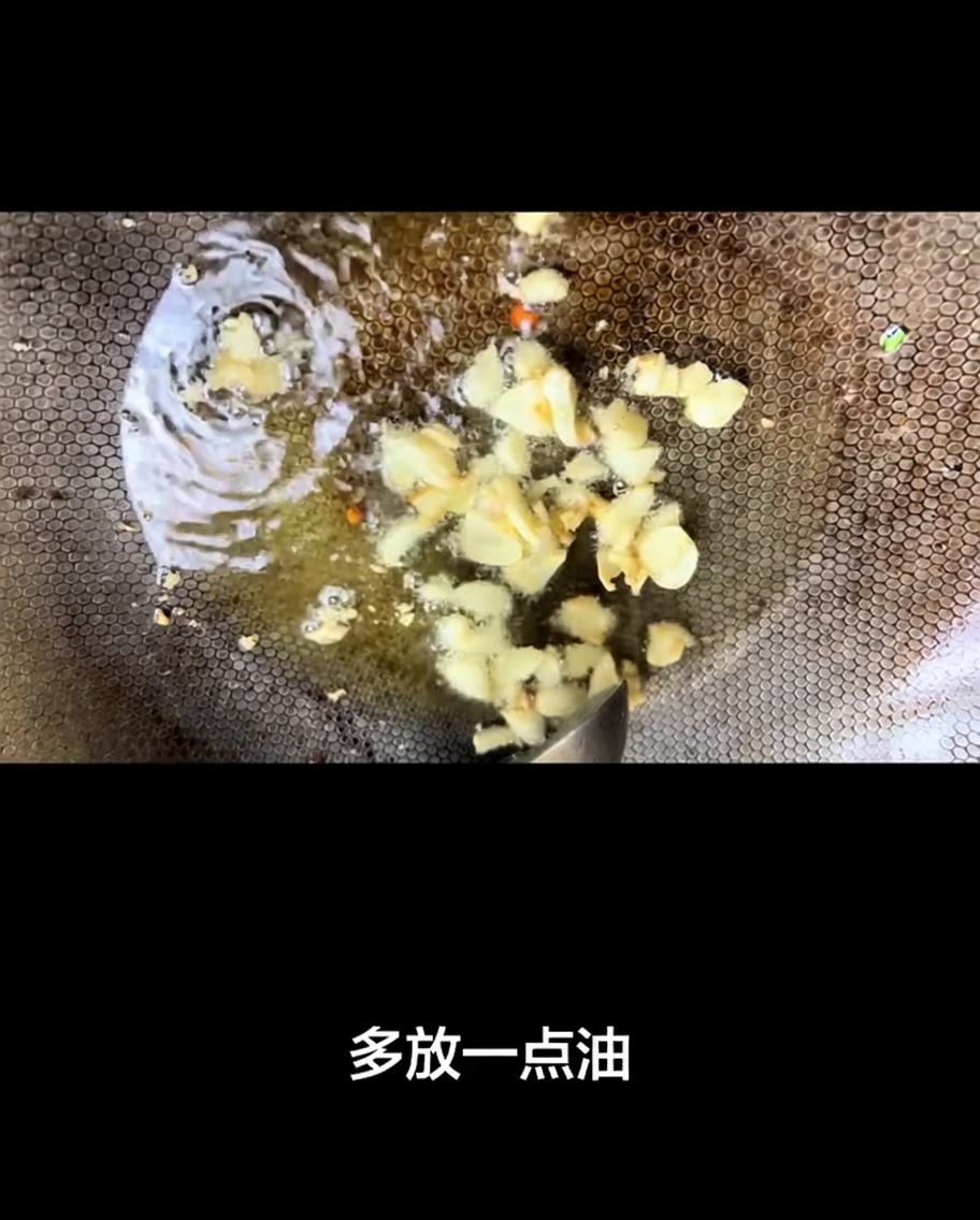 Láminas de ajo friéndose en aceite caliente dentro de un wok.