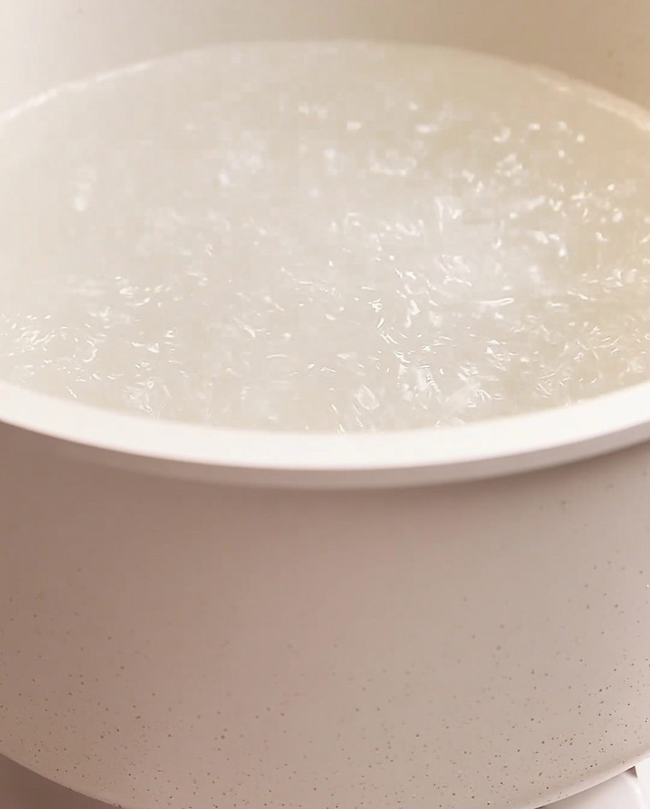 Espaguetis cocinándose en una olla grande con agua hirviendo y burbujas visibles.