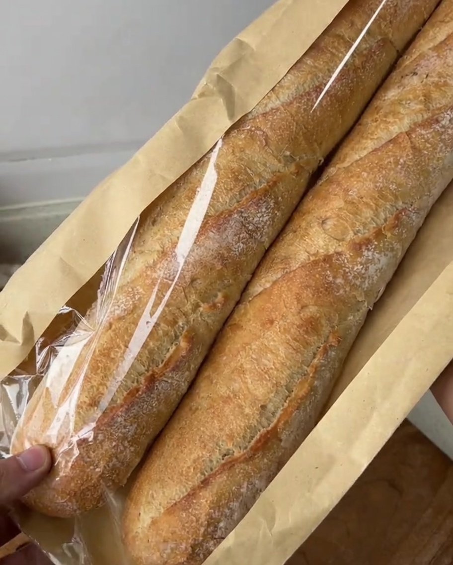 Rebanadas diagonales de baguette sobre una tabla de cortar, listas para la mezcla de mantequilla de ajo.