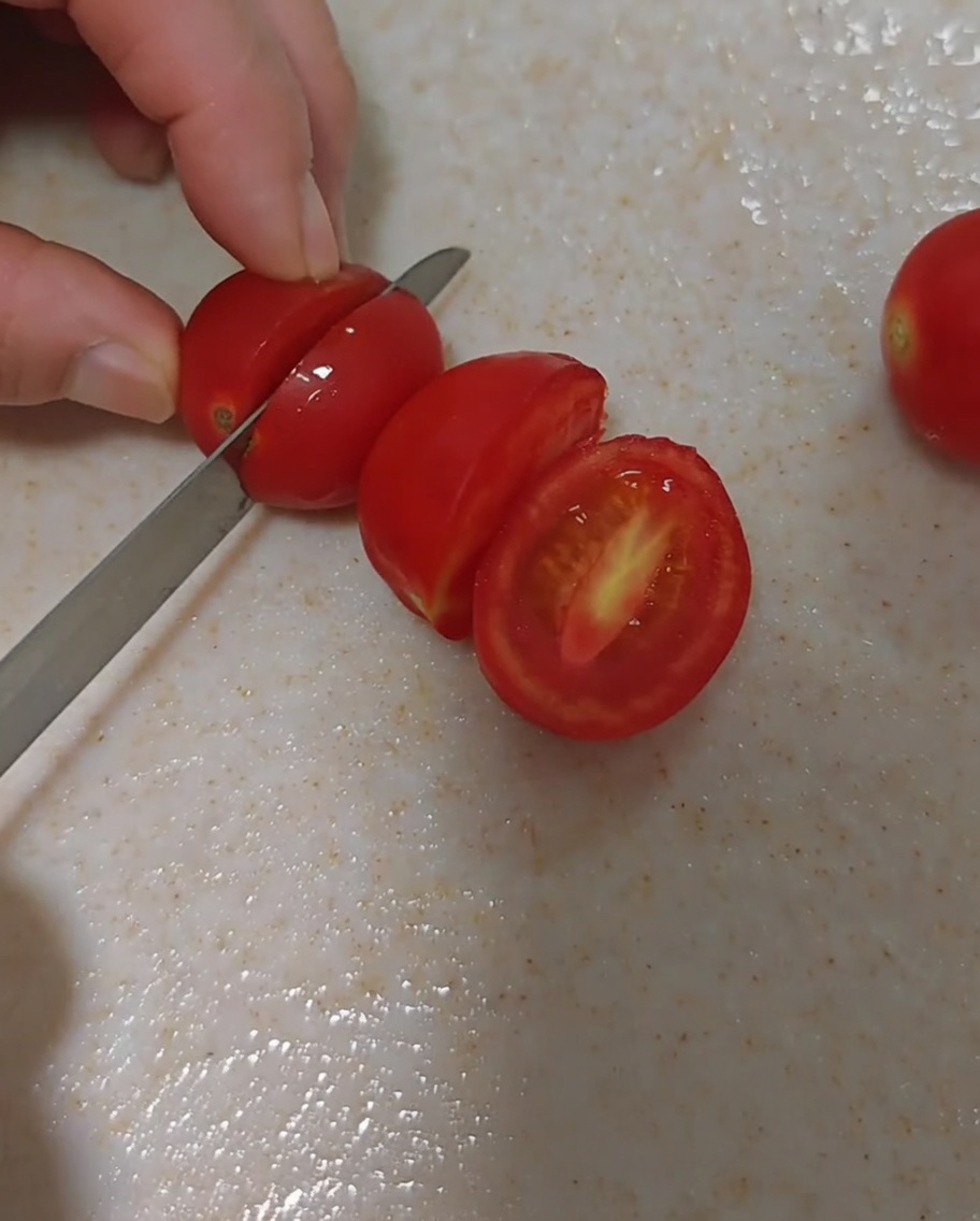 Tomates cherry frescos siendo cortados cuidadosamente por la mitad.