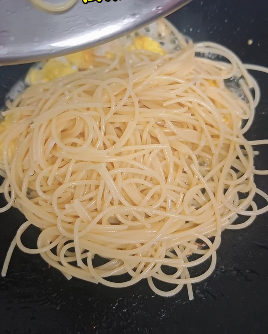 Ramilletes de brócoli escaldados y tomates cherry cortados añadidos al wok con los espaguetis y los huevos.