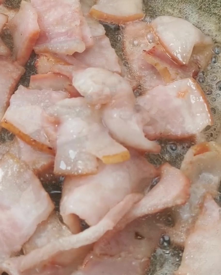 Tomates cherry frescos añadidos a la sartén con el bacon dorado.