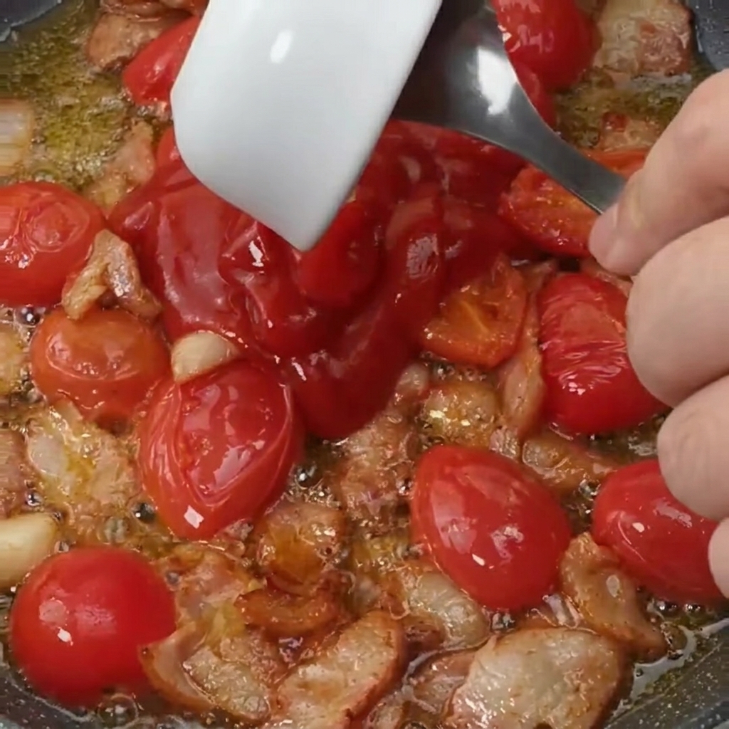 Salsa de tomate y un toque de azúcar añadidos a la sartén con bacon y tomates.
