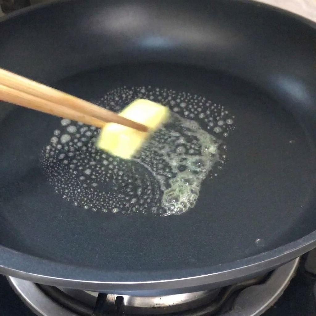 Un trozo de mantequilla derritiéndose en una sartén caliente.