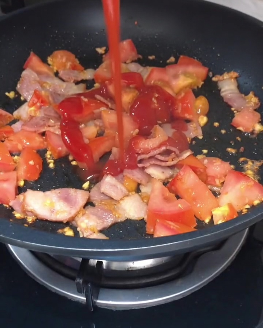 Ketchup y salsa de soja vertidos sobre la mezcla de tomate y bacon.