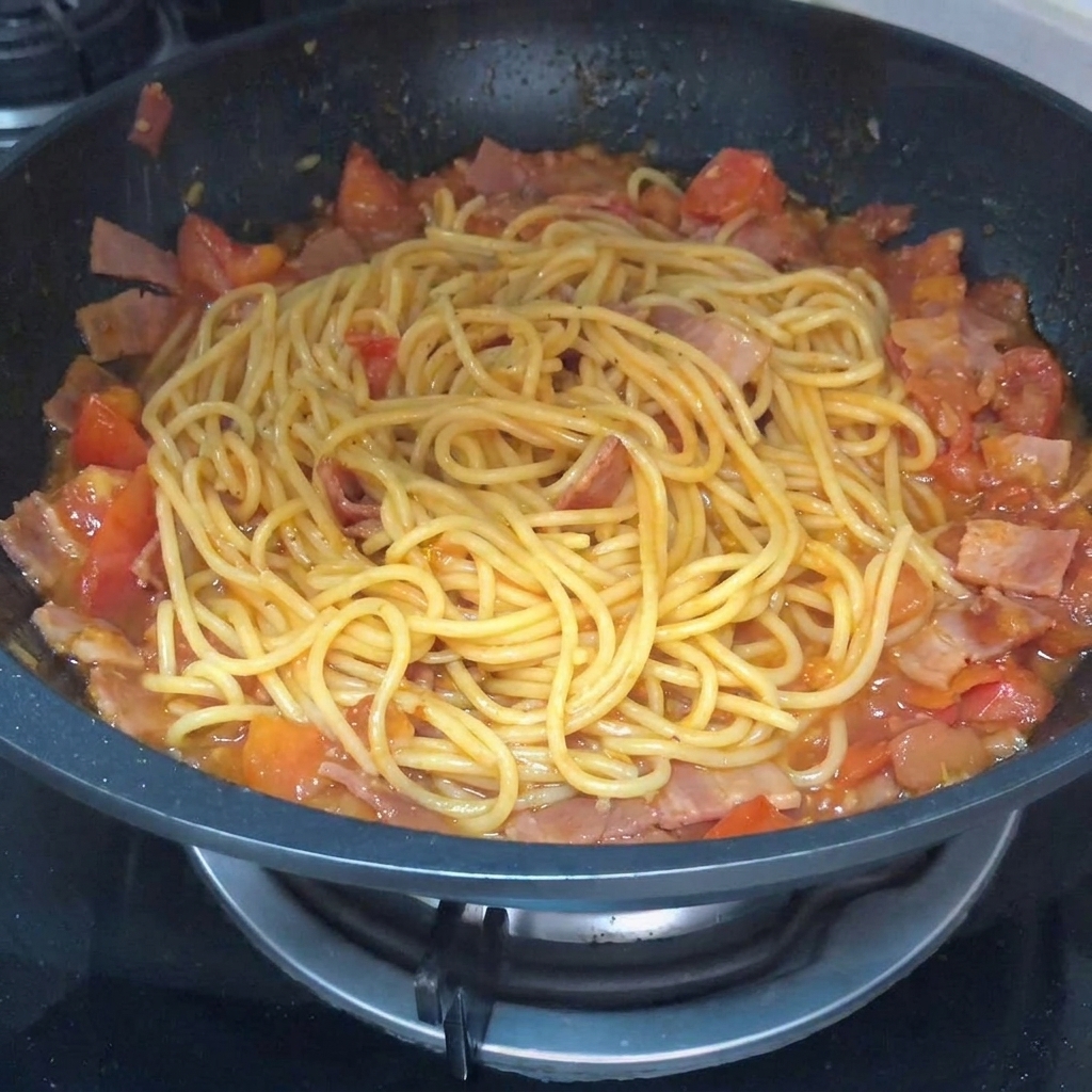 Primer plano de la pasta siendo mezclada con pimienta negra espolvoreada por encima.