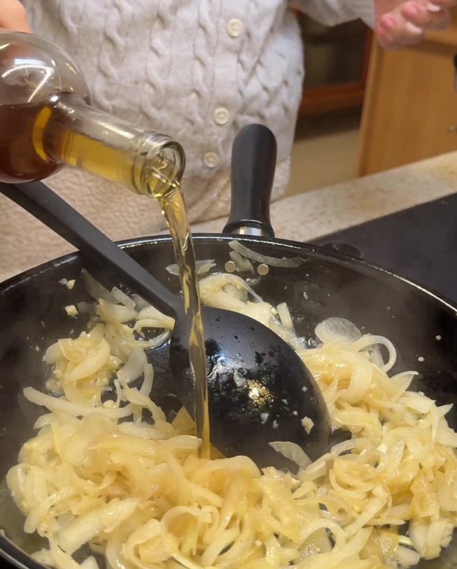 Vino blanco y vinagre balsámico siendo vertidos sobre las cebollas y el ajo.