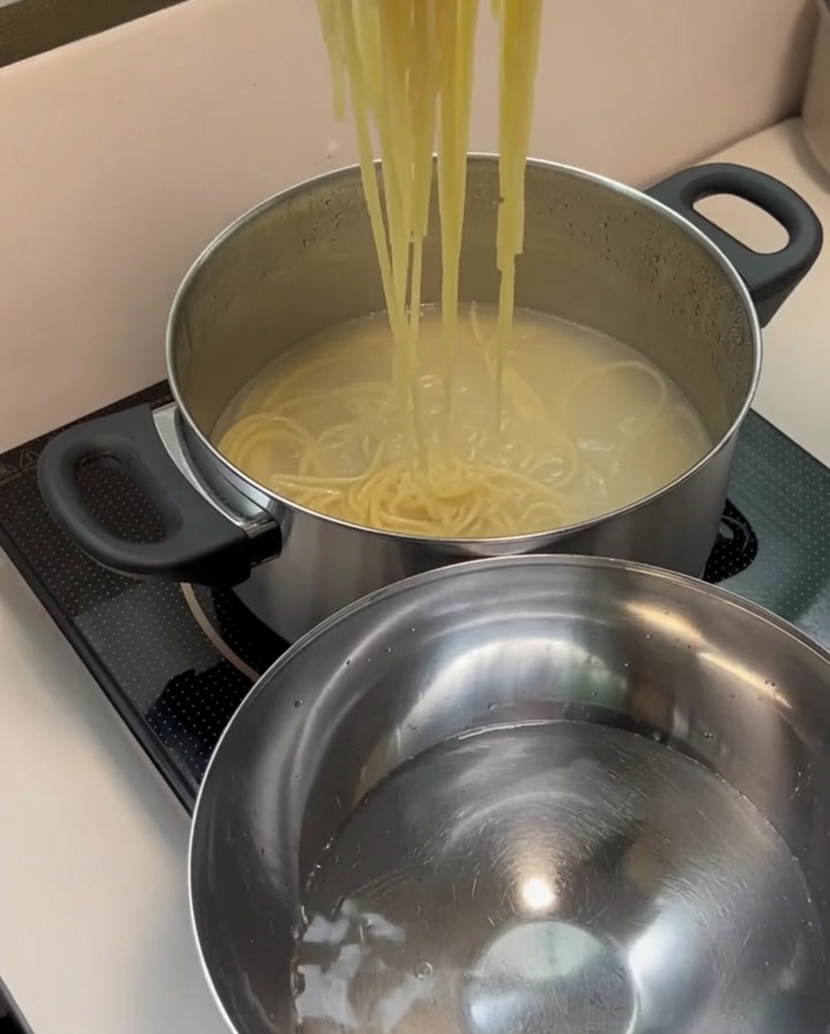 Espaguetis cocidos siendo trasladados a un bol con agua fría.