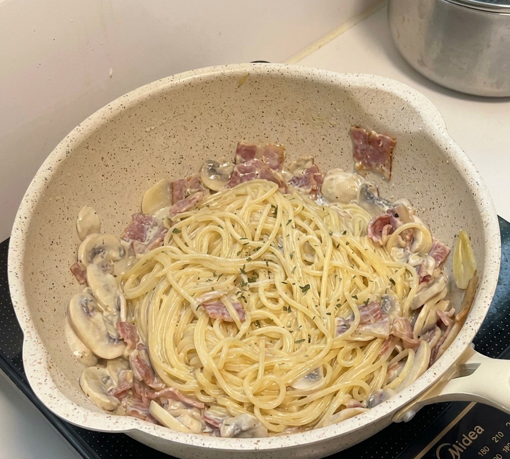 Plato final de pasta con champiñones en la sartén, decorado con hierbas y listo para servir.