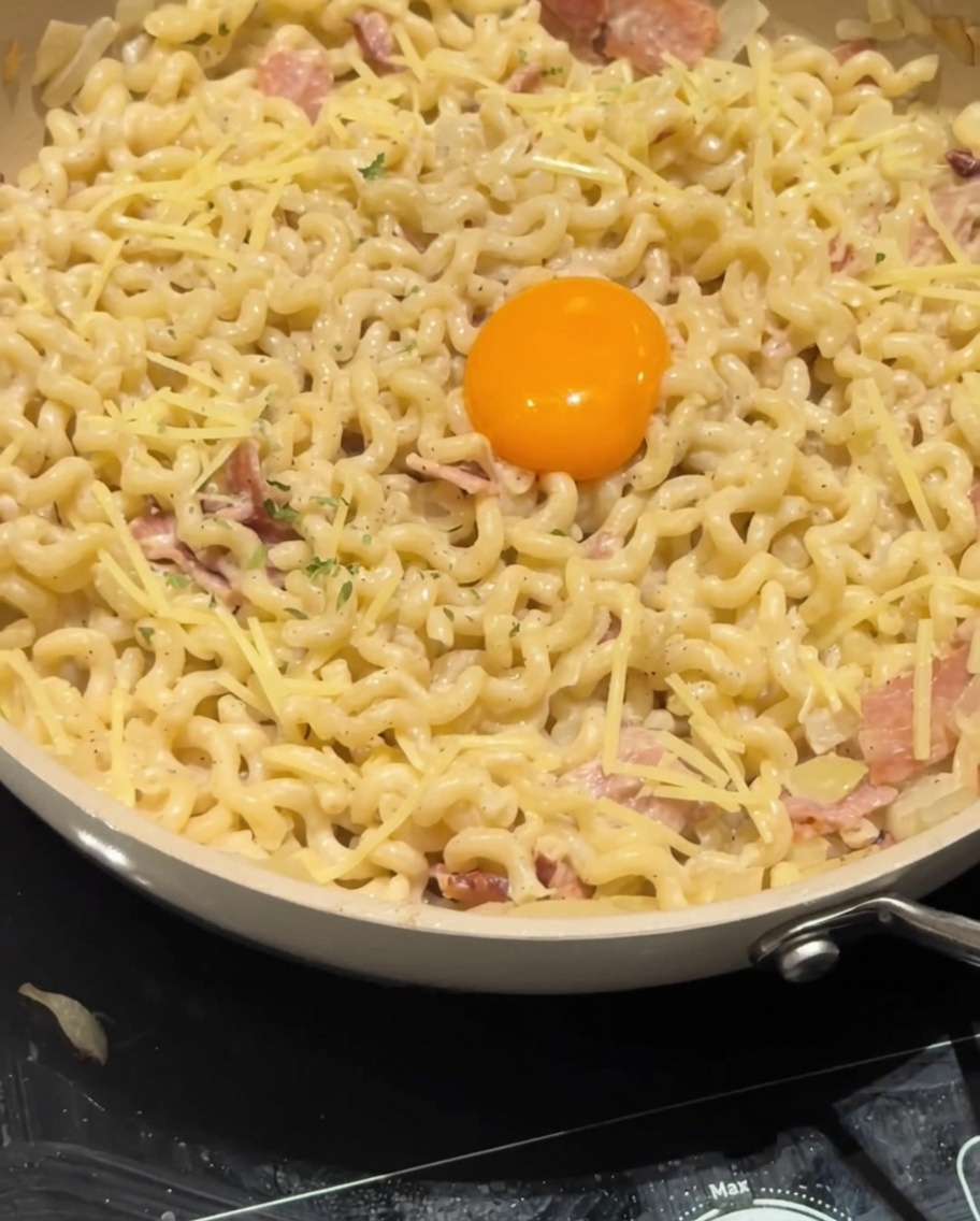 Perejil seco siendo espolvoreado sobre la yema de huevo y la pasta carbonara cremosa como guarnición final.