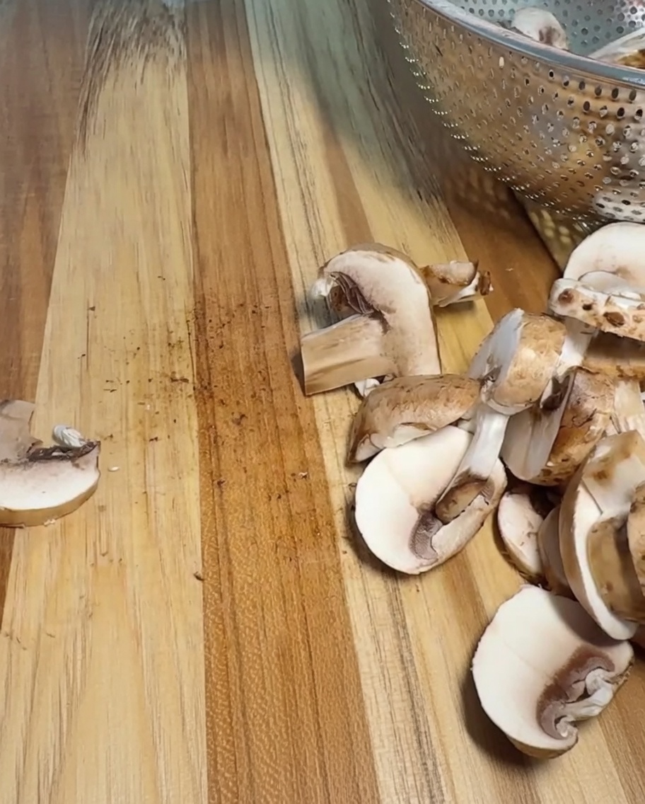 Una cebolla siendo cortada cuidadosamente en trozos uniformes sobre una tabla de cortar de madera.