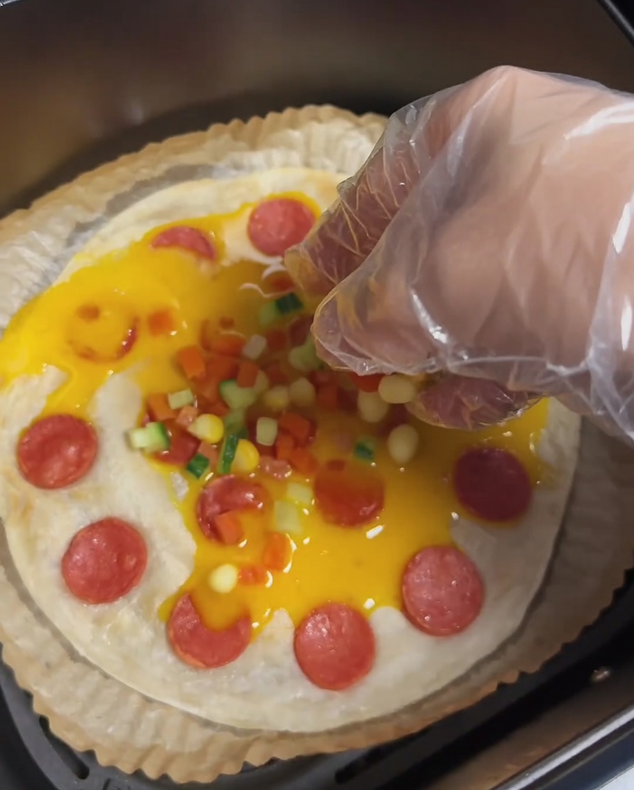 Una tortita de cebolleta con huevo, salchicha y coloridos trozos de zanahoria, pepino y granos de maíz.
