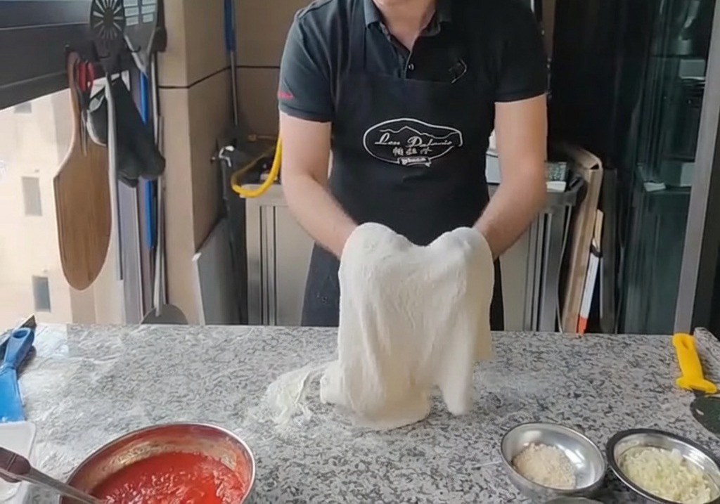 Estirando la masa sobre los nudillos de ambas manos, manteniéndola verticalmente.