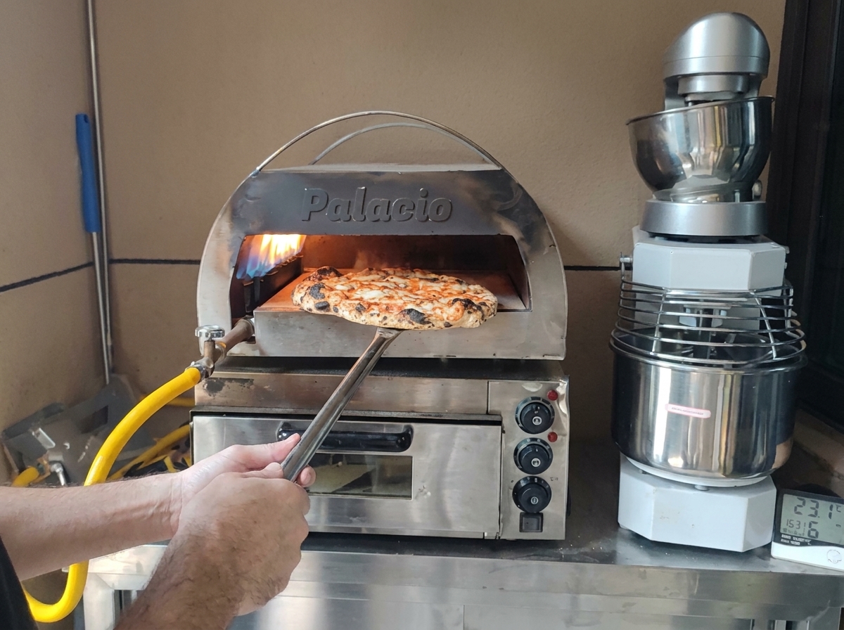 Una pizza perfectamente horneada con la corteza carbonizada siendo retirada del horno con una pala metálica.