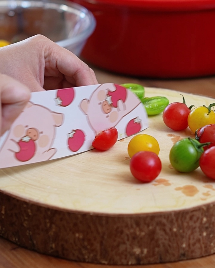 Tomates cherry cortándose por la mitad sobre una tabla de madera.