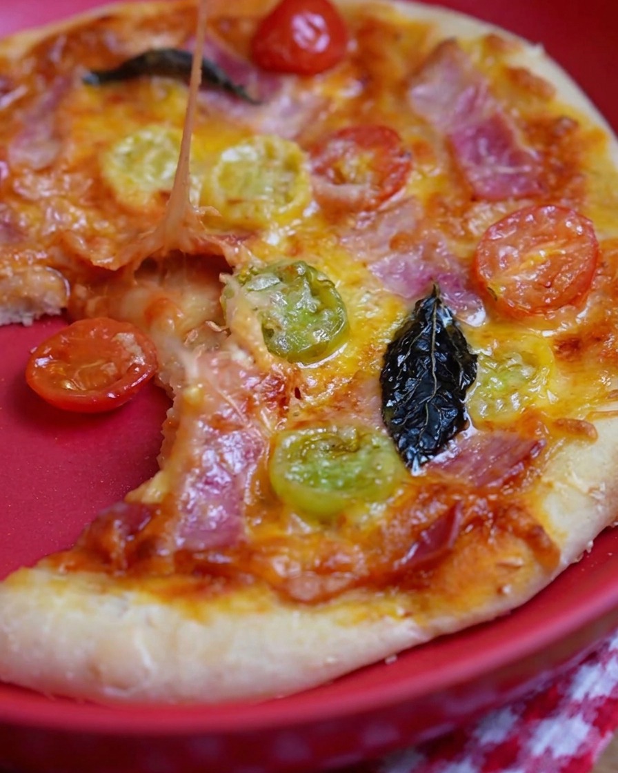 Cuchara metálica extendiendo salsa de tomate roja sobre la base de masa.