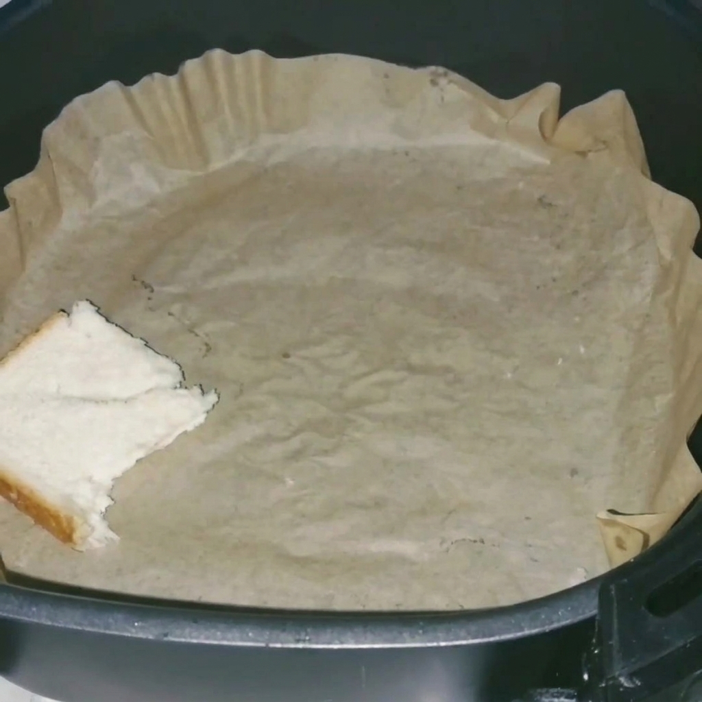 Primer plano de piezas de pan de molde dispuestas ordenadamente en una cesta de air fryer forrada con papel de horno.