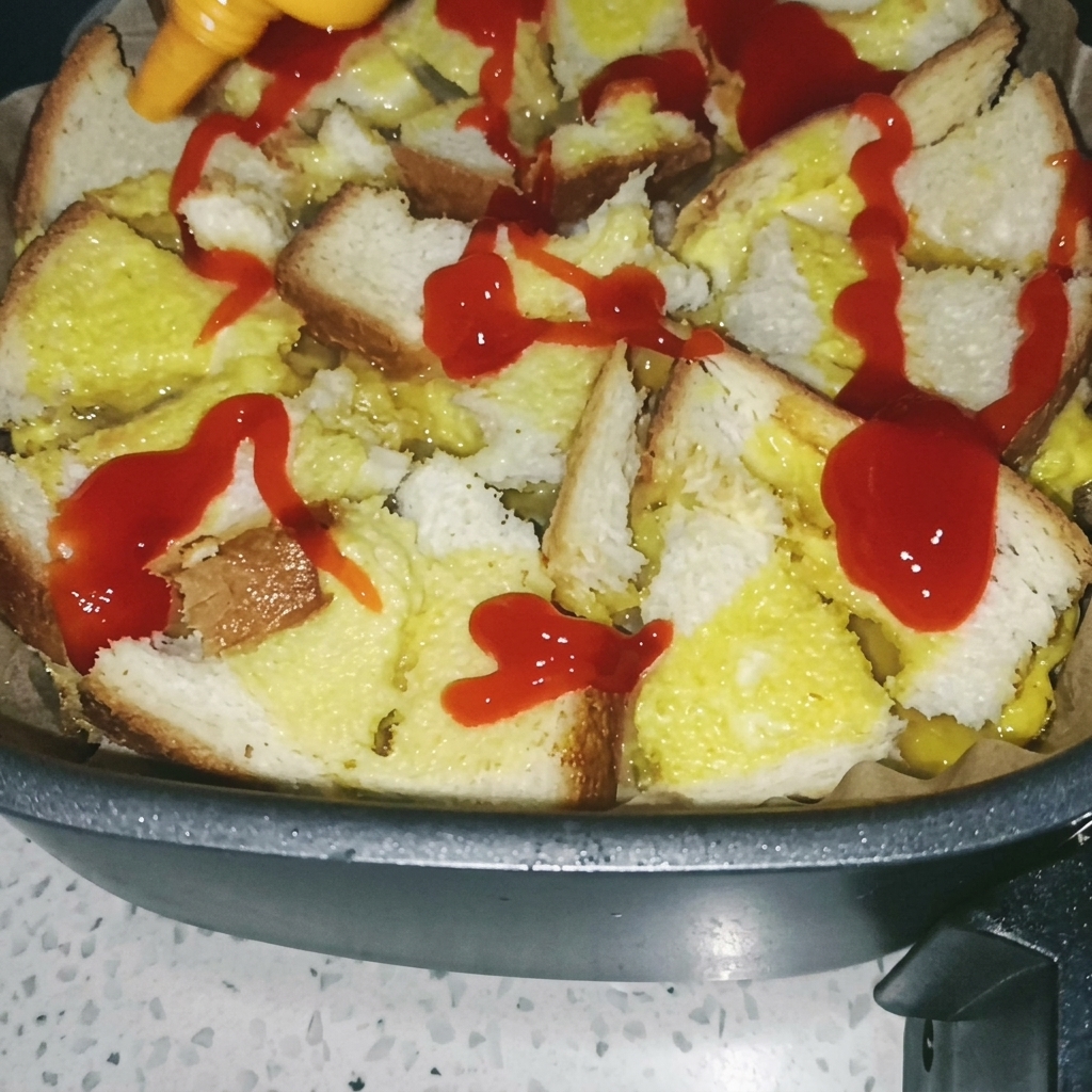 Un pincel extendiendo salsa de tomate roja sobre la base de pan y huevo cocida en la freidora.