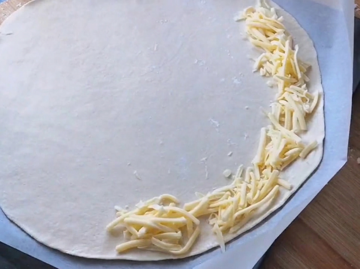 Salsa blanca siendo extendida sobre una base de pizza redonda.