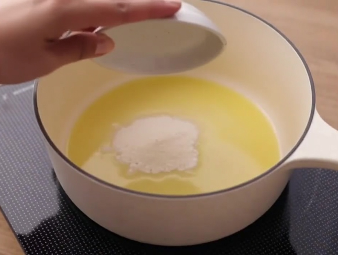 Harina siendo mezclada con mantequilla derretida en una cacerola, formando una pasta.