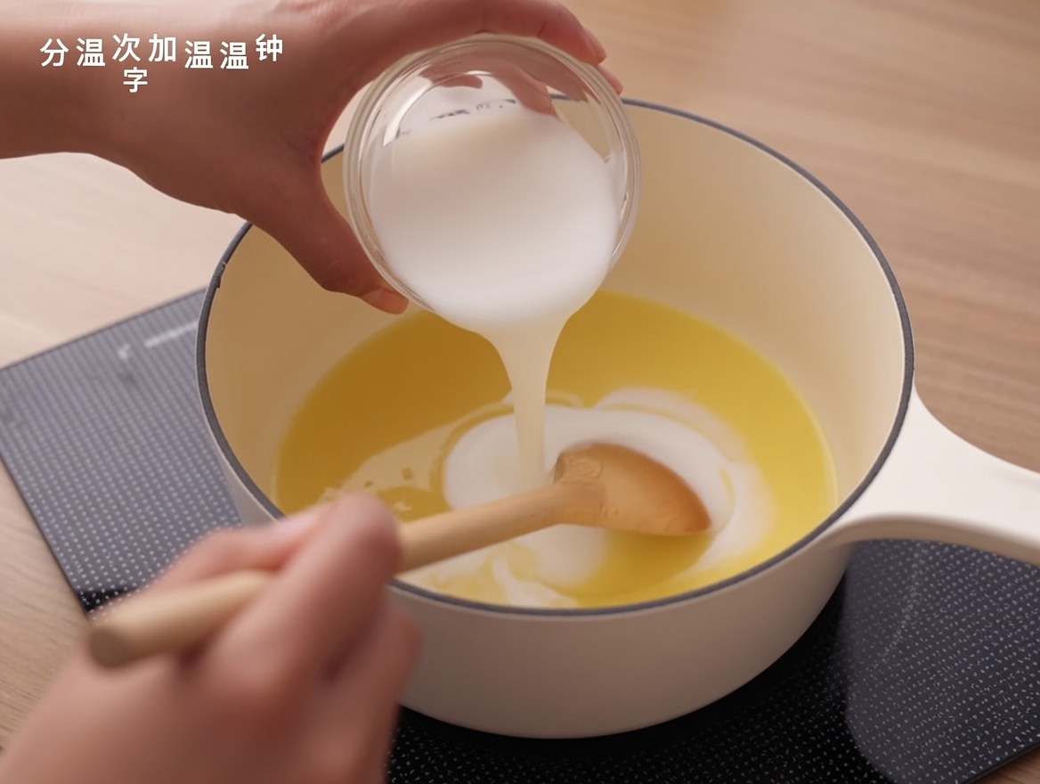 Leche siendo vertida en una base de roux en una cacerola, siendo mezclada con una cuchara de madera.