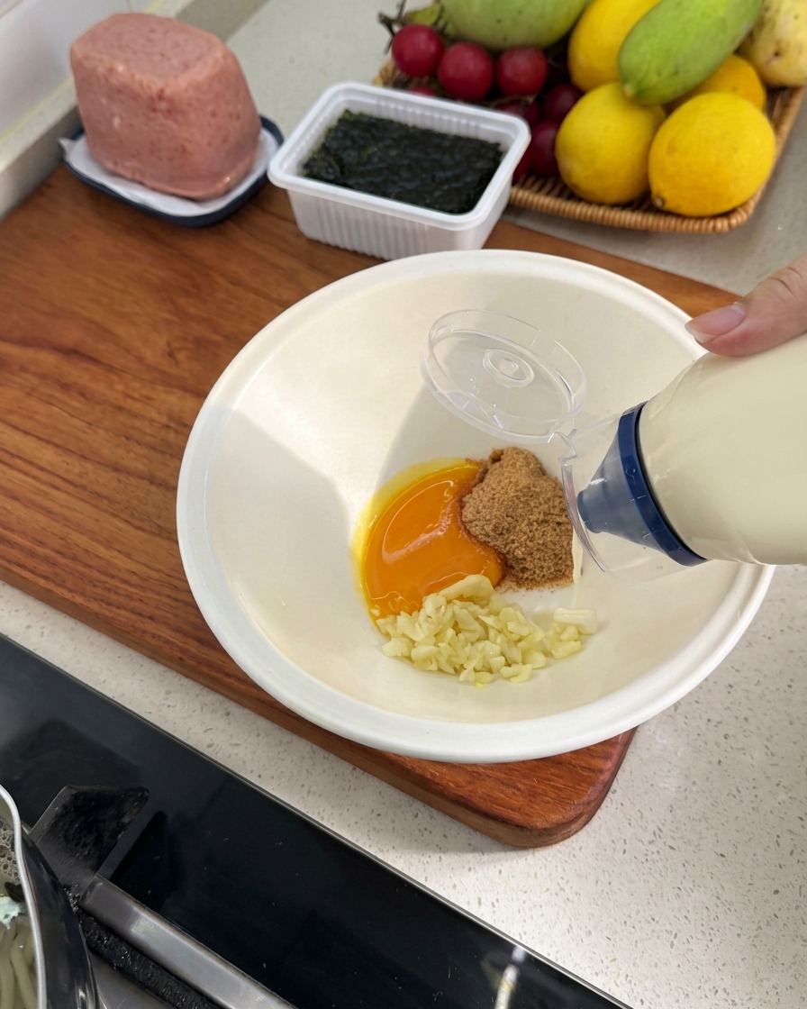 Mayonesa siendo añadida desde una botella a la mezcla de ingredientes.
