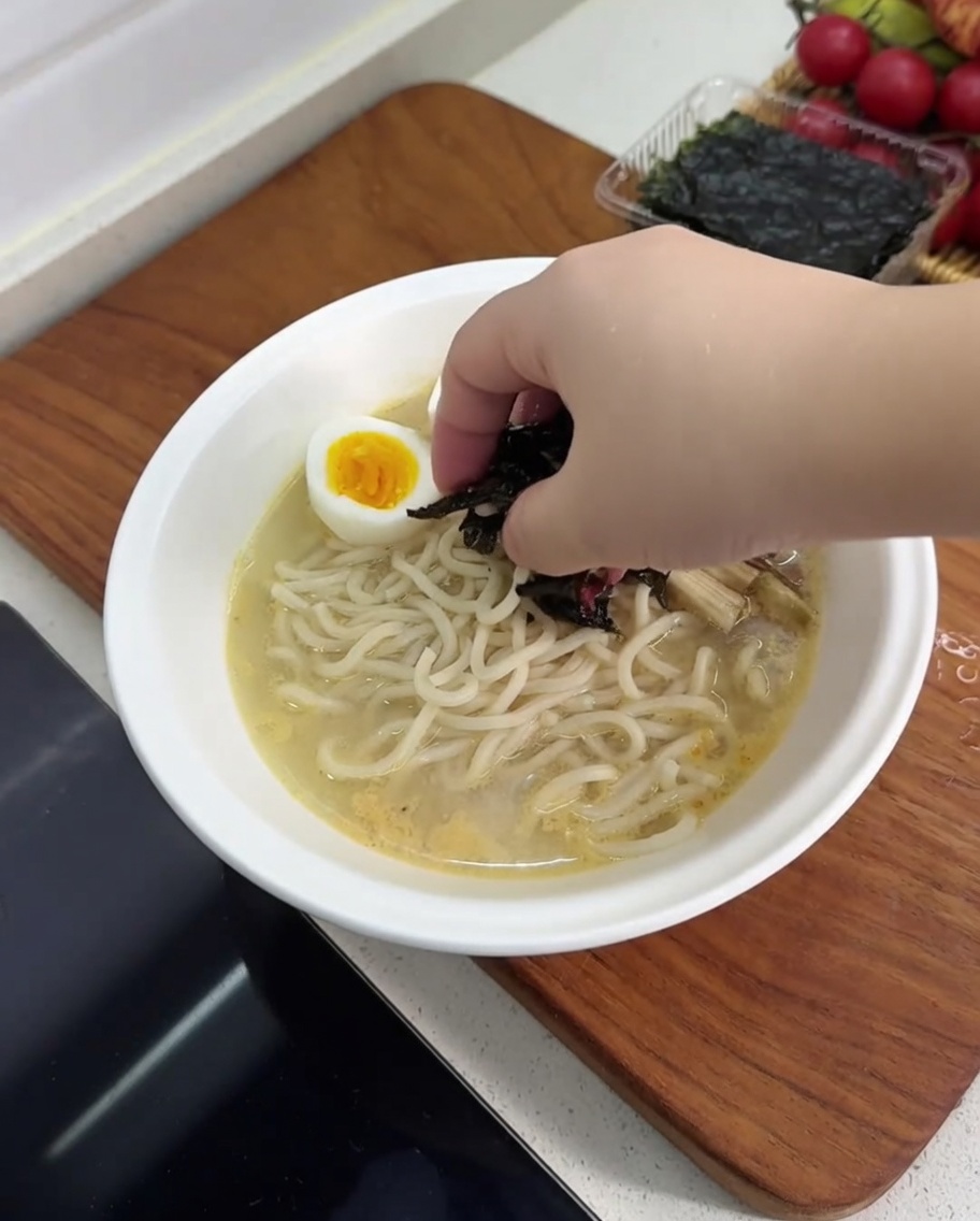 Tazón de ramen terminado con huevo, vegetales y alga nori.