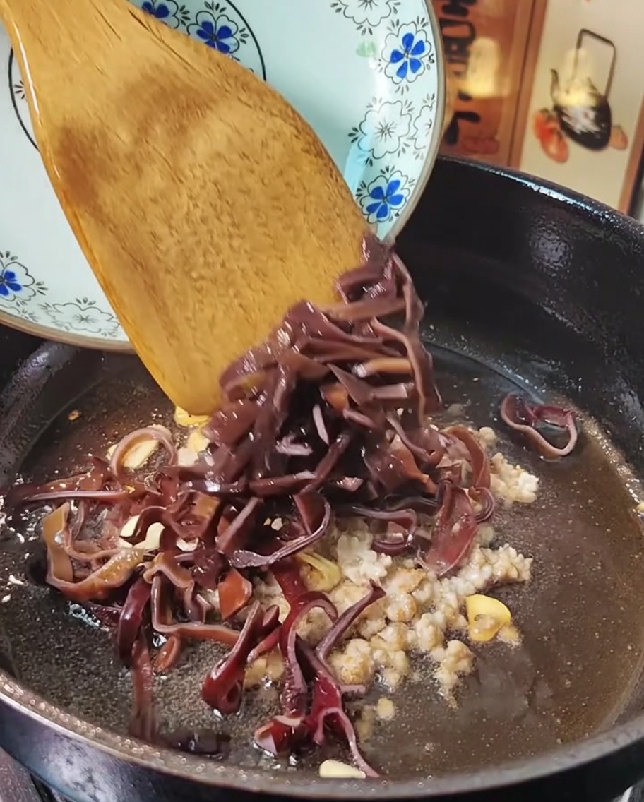 Carne picada y hongos salteándose en una sartén con una espátula.