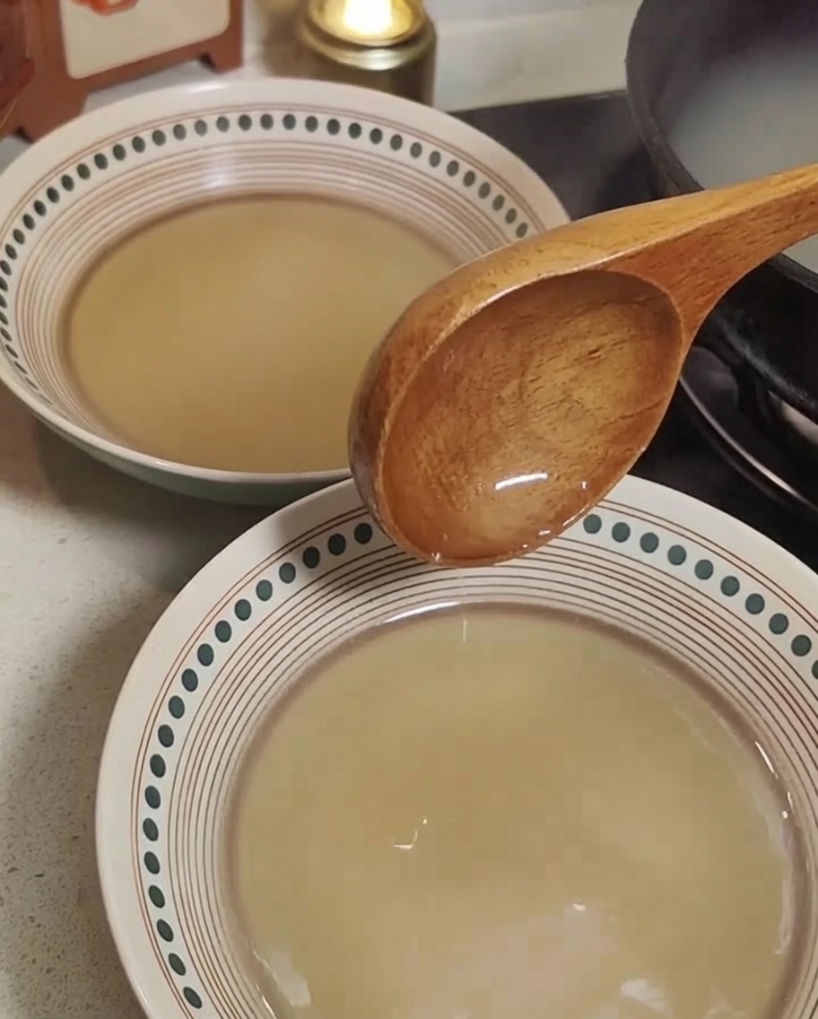 Fideos de ramen cocidos siendo añadidos a cuencos con caldo caliente.