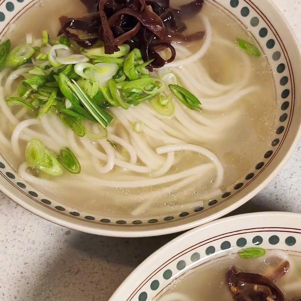 Un cuenco de ramen casi terminado con carne, hongos y cebollino.