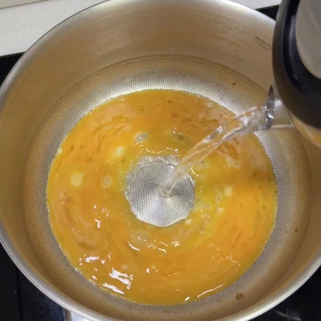 Agua hirviendo siendo vertida en la olla con la base tonkotsu, creando un caldo cremoso.