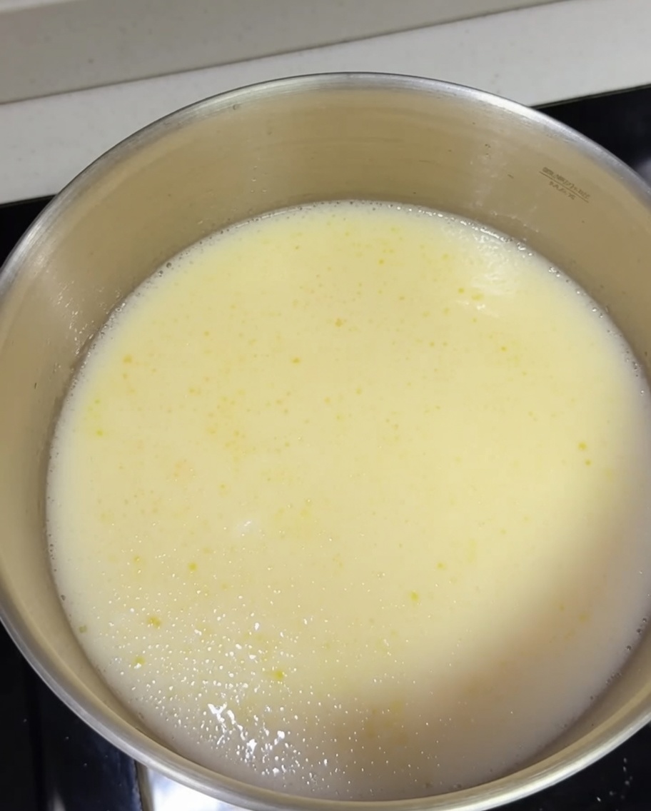 Fideos de ramen cocidos siendo añadidos a la olla con el caldo tonkotsu hirviendo.
