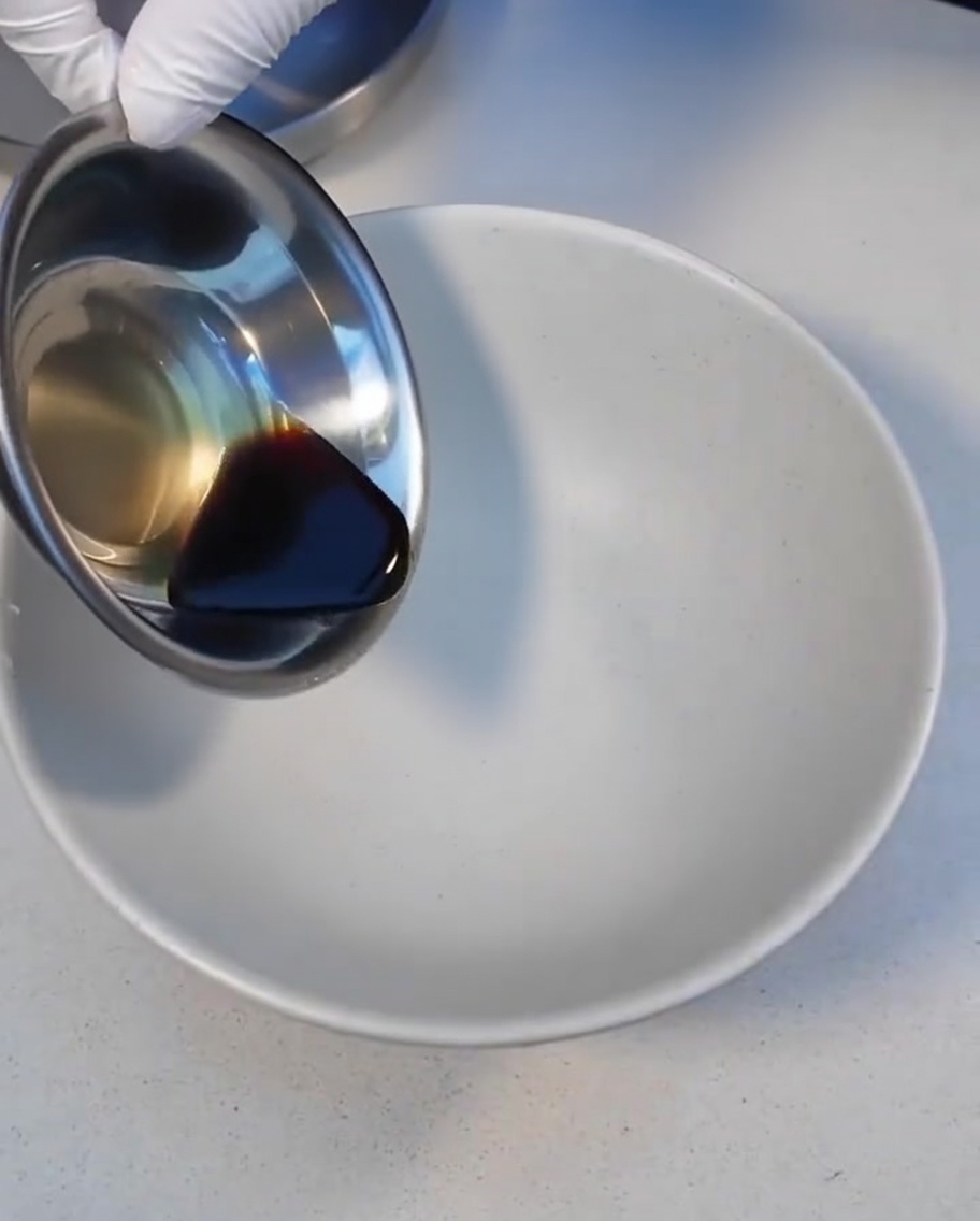 Salsa oscura Char Siu vertiéndose en un tazón blanco.