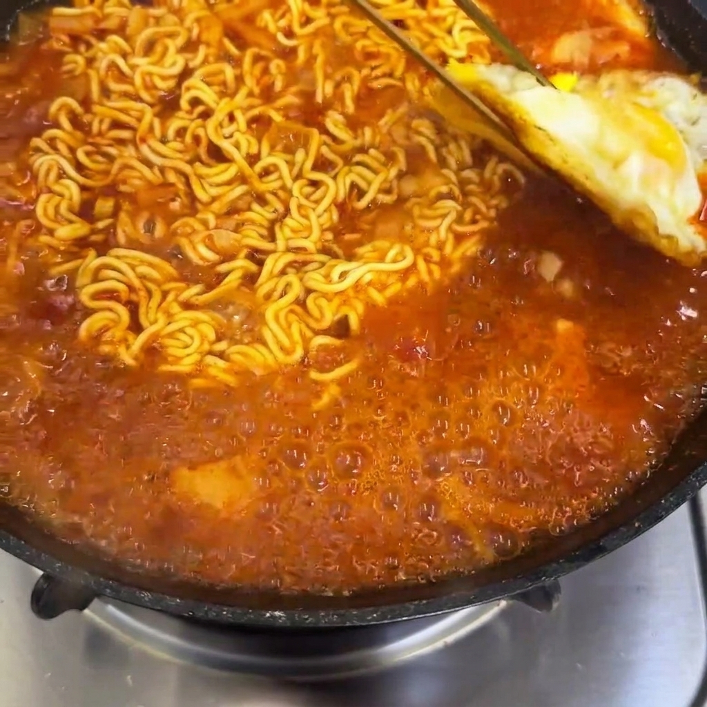 Huevos fritos colocados cuidadosamente sobre el ramen hirviendo.