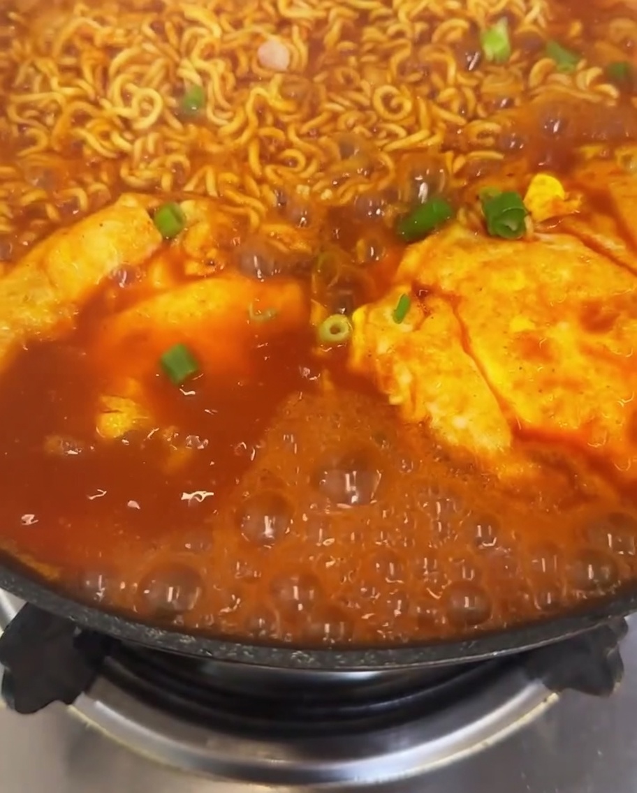 Un primer plano del ramen con kimchi decorado con cebolletas y chile.
