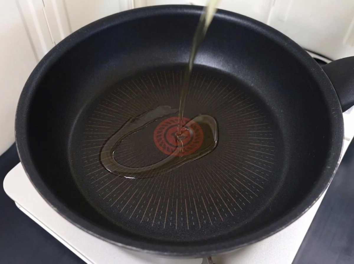 Carne de cerdo en rodajas finas dorándose en una sartén con aceite caliente.