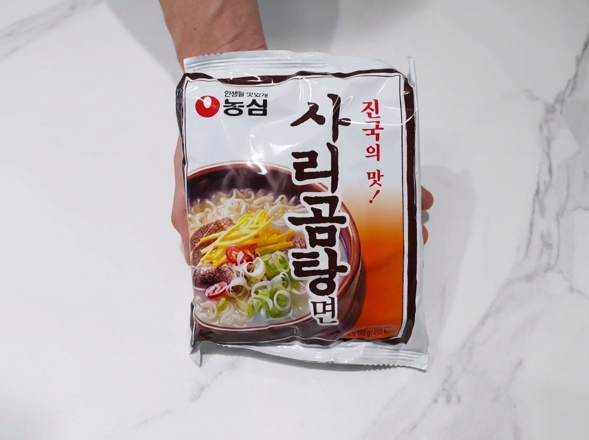 Un bloque de fideos ramen añadido al caldo hirviendo de cerdo y kimchi.