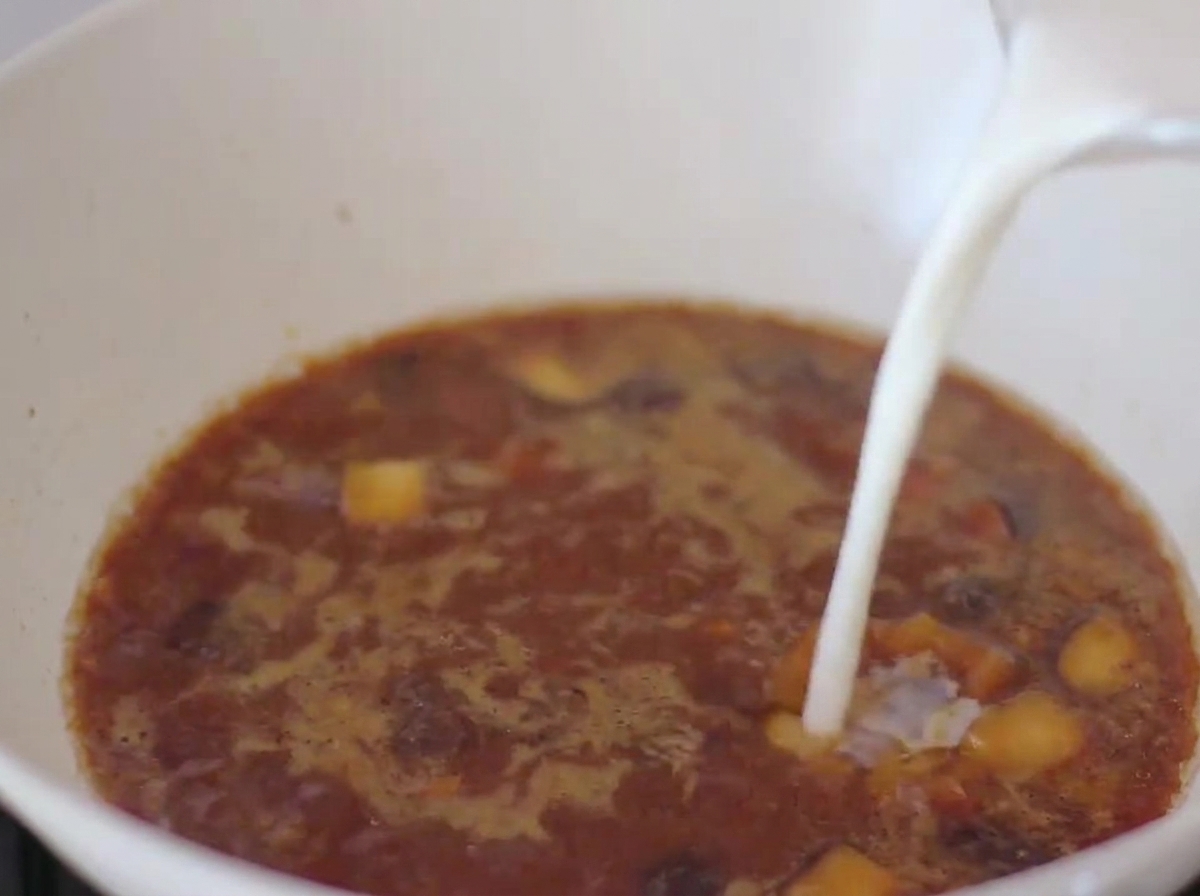 Leche siendo vertida en el caldo a base de miso dentro de la sartén.
