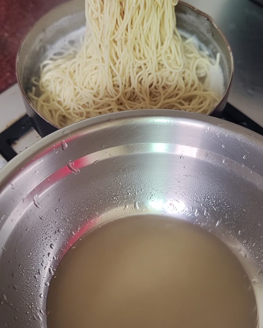 Sacando los fideos cocidos de una olla con palillos.