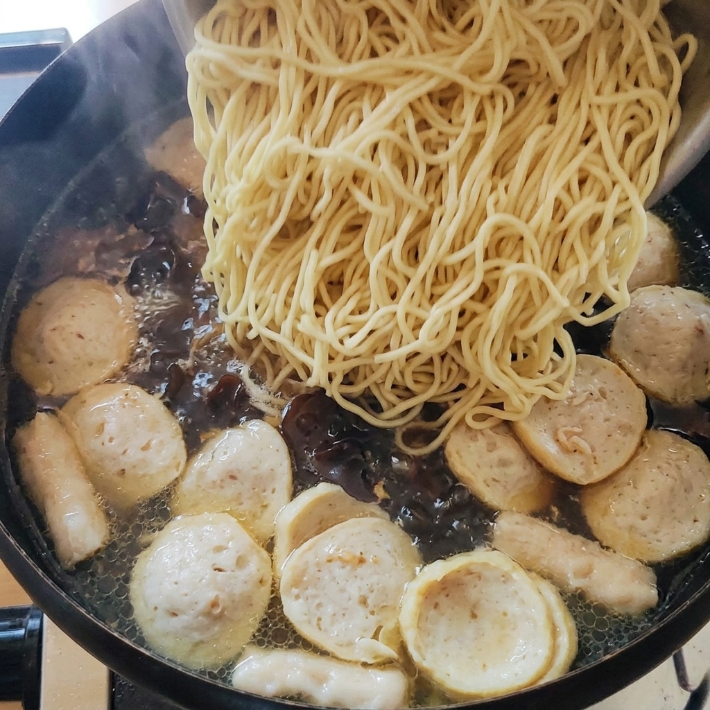 Añadiendo los fideos cocidos a la olla con sopa.