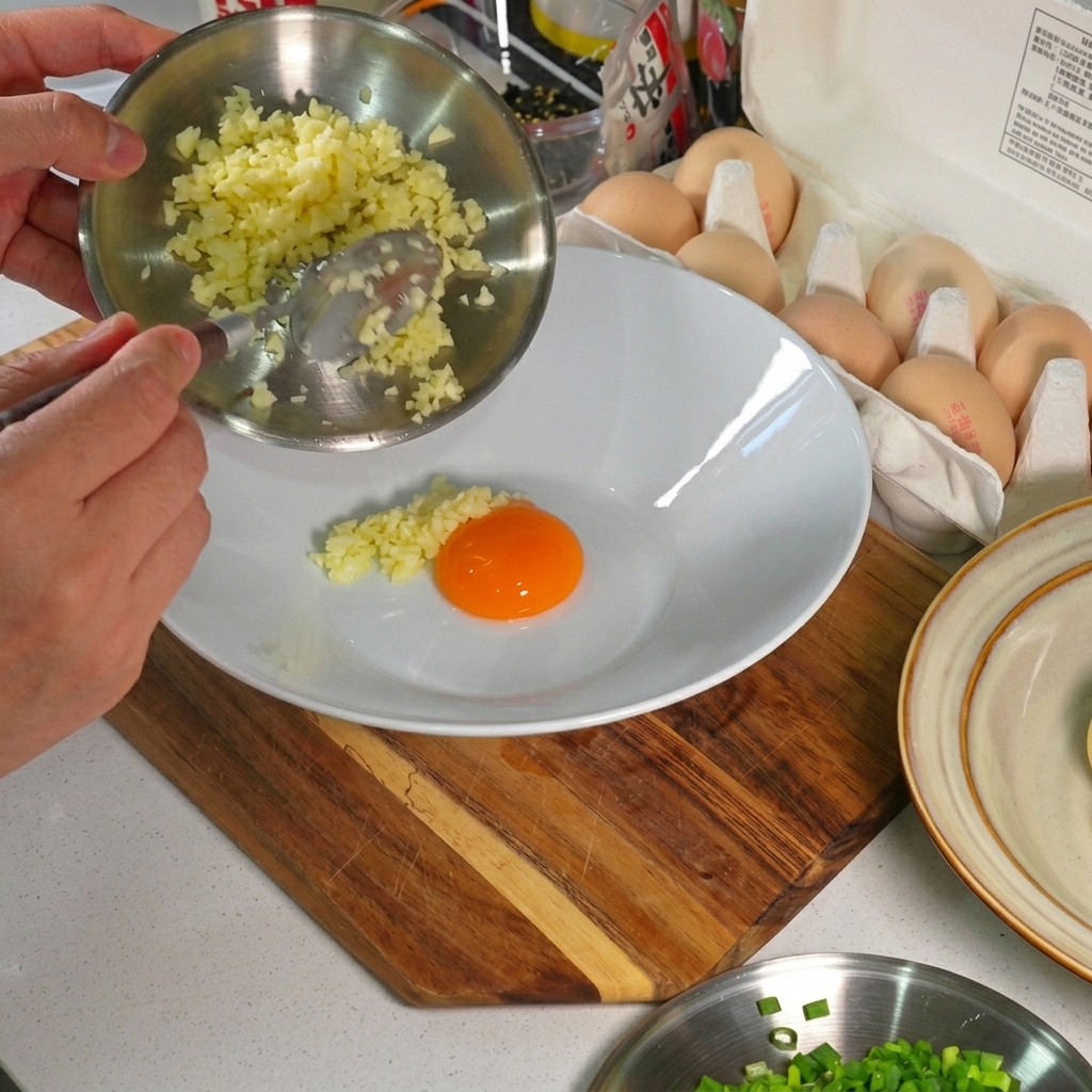 Un tazón con una yema de huevo rodeada de ajo picado, cebolleta picada, un paquete de condimento para ramen y un toque de mayonesa.