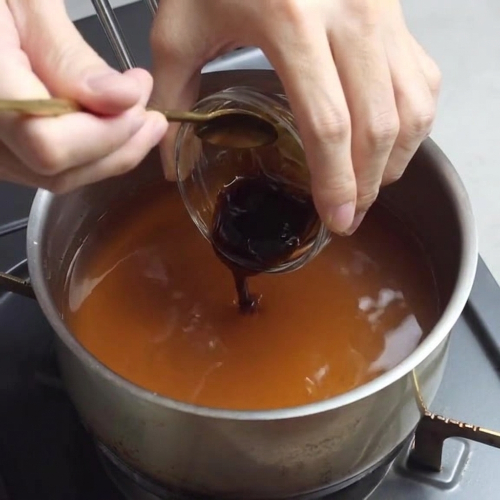 Añadiendo salsa de ostras a la mezcla de caldo para ramen.
